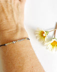 Morse Code Beaded Bracelet - Be You on black cord on a woman's wrist