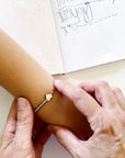 Woman putting an 'I love you' Morse Code and charm beaded bracelet on a child