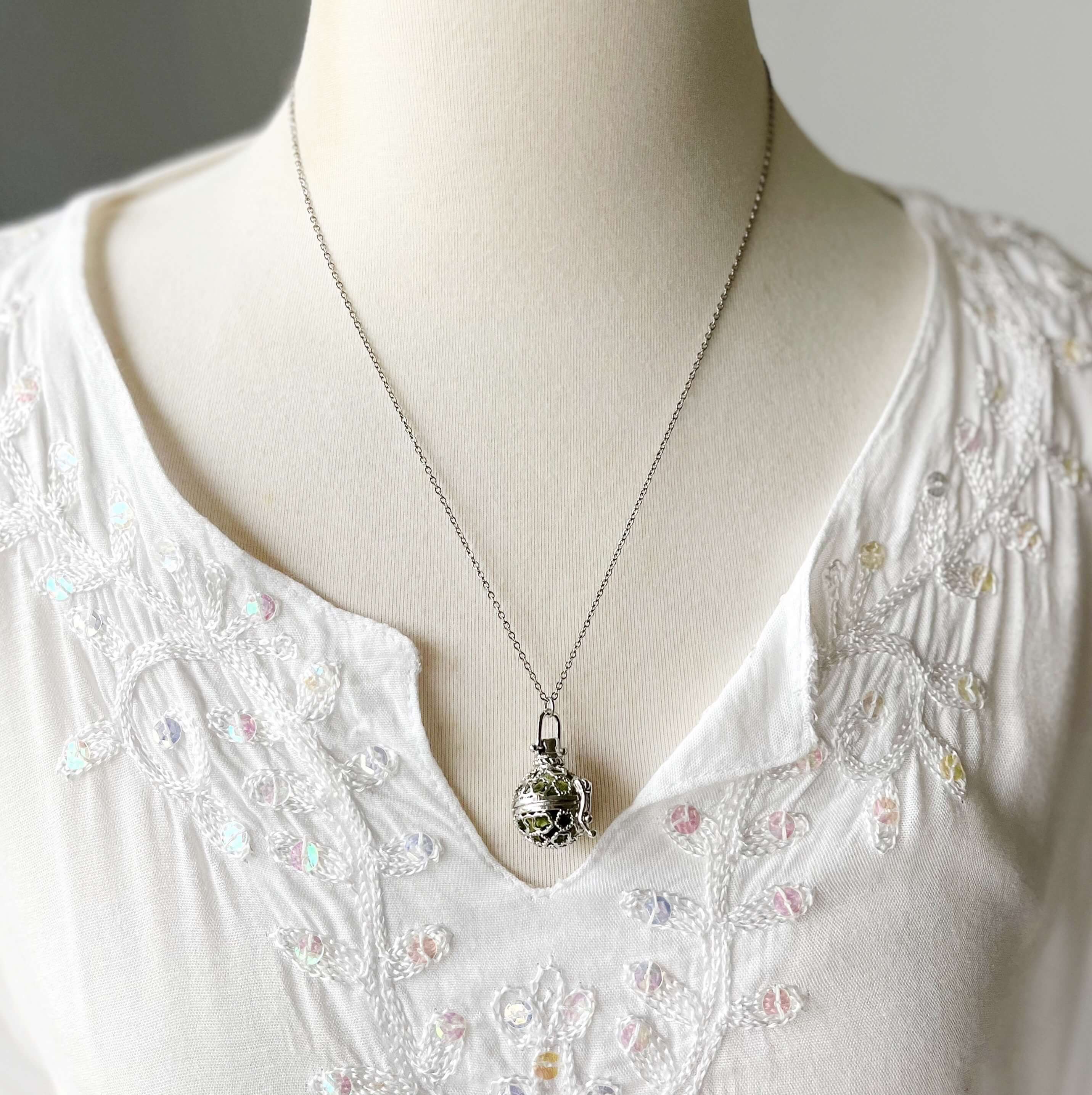 Round cage locket with green ribbon inside - Write Your Wish Necklace - on a mannequin