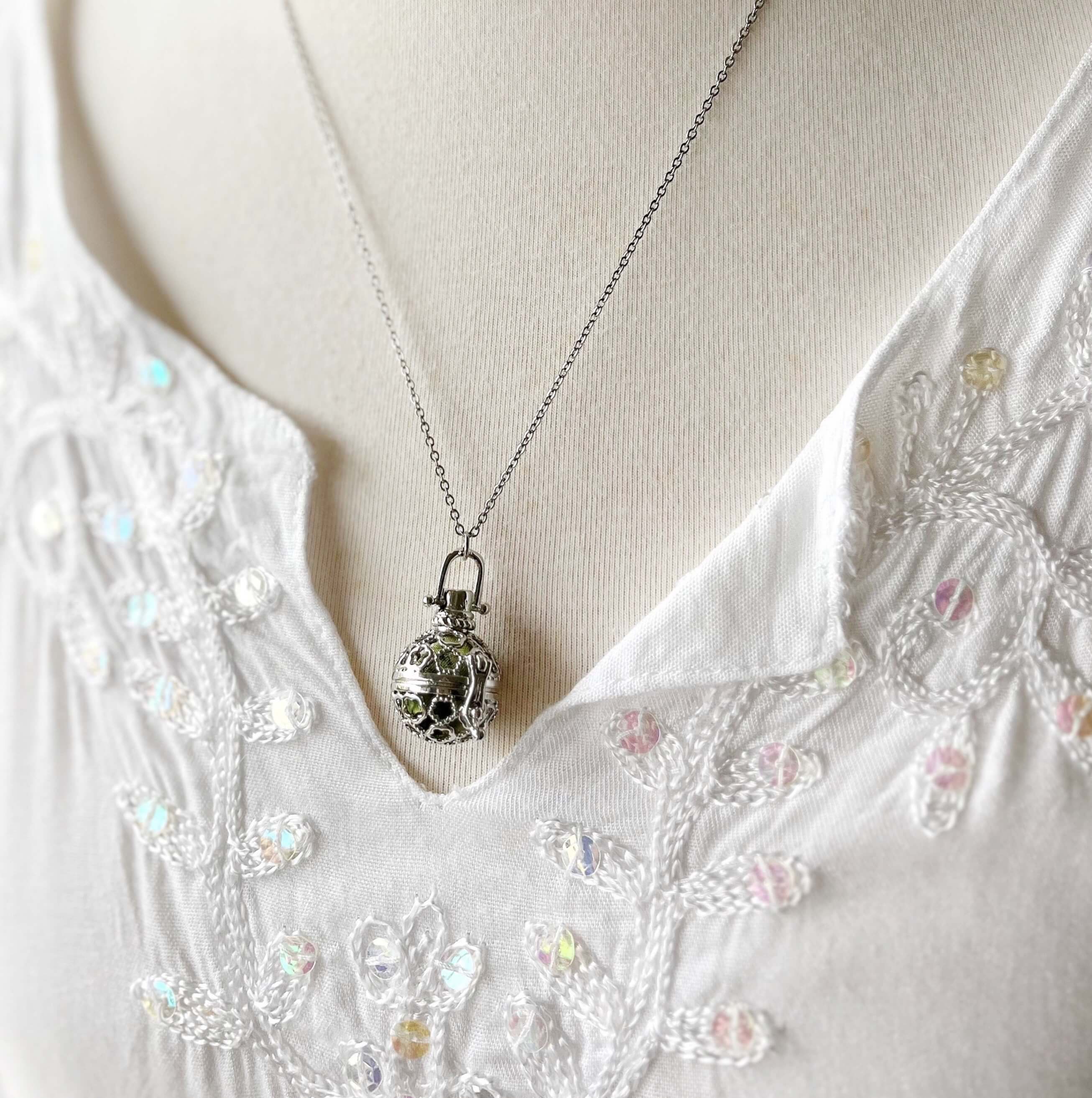 Round cage locket with green ribbon inside - Write Your Wish Necklace - on a model