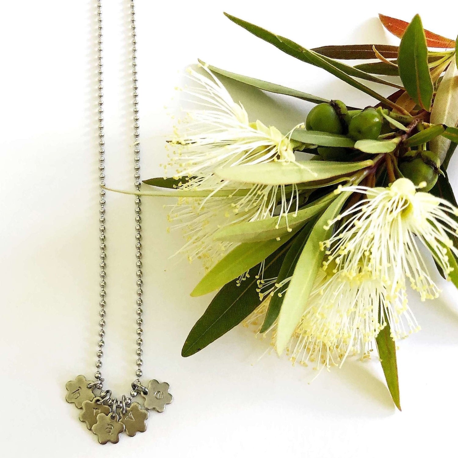 Flower charm necklace on ball chain stamped with "brave"