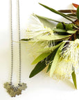 Flower charm necklace on ball chain stamped with "brave"