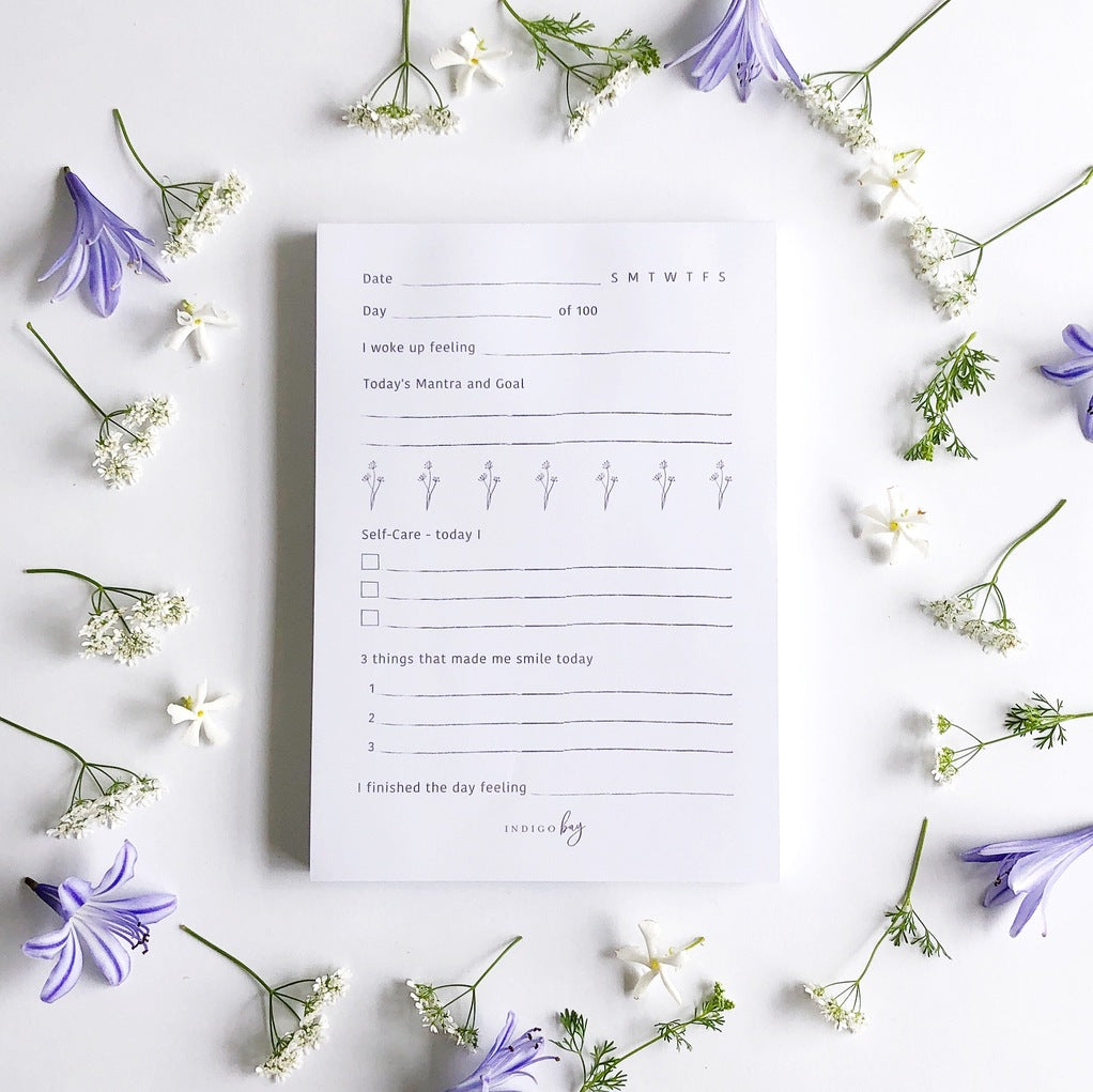 White self-care notepad with lilac text and flowers.