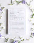 White self-care notepad with lilac text and flowers.