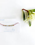 Loved Morse code beaded bracelet on pink cord on a white card with blue text