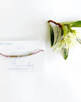 Be you beaded bracelet on a white card with blue text